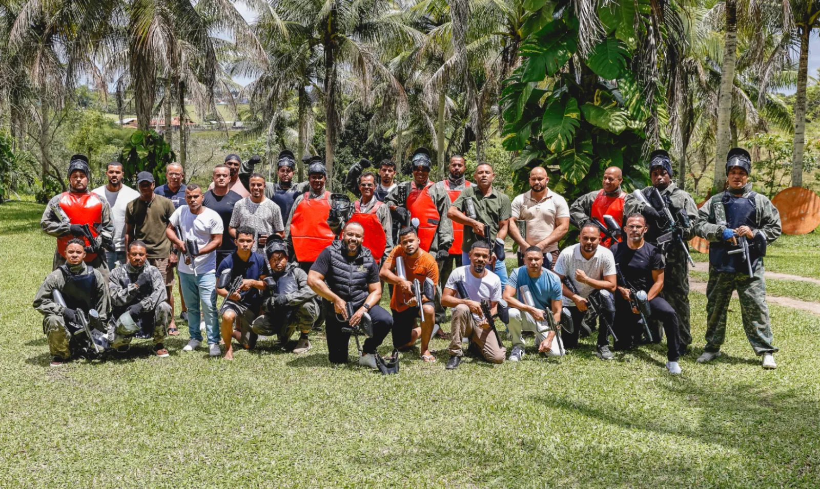 Grupo de homens reunidos após partida de paintball em área verde durante o RC2